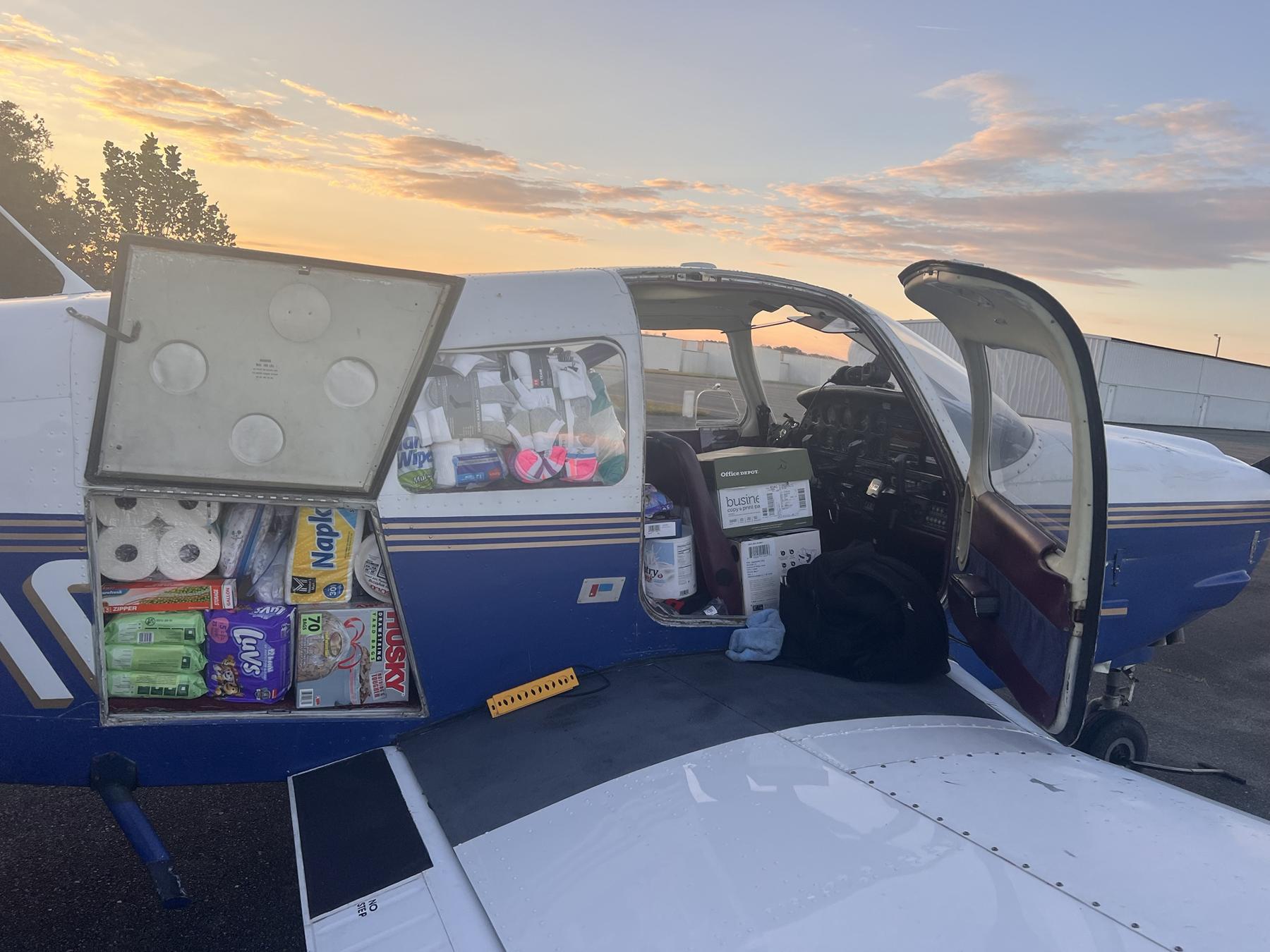 Diapers, paper towels, socks and other supplies packed into the baggage compartment and cabin of the Piper at sunrise