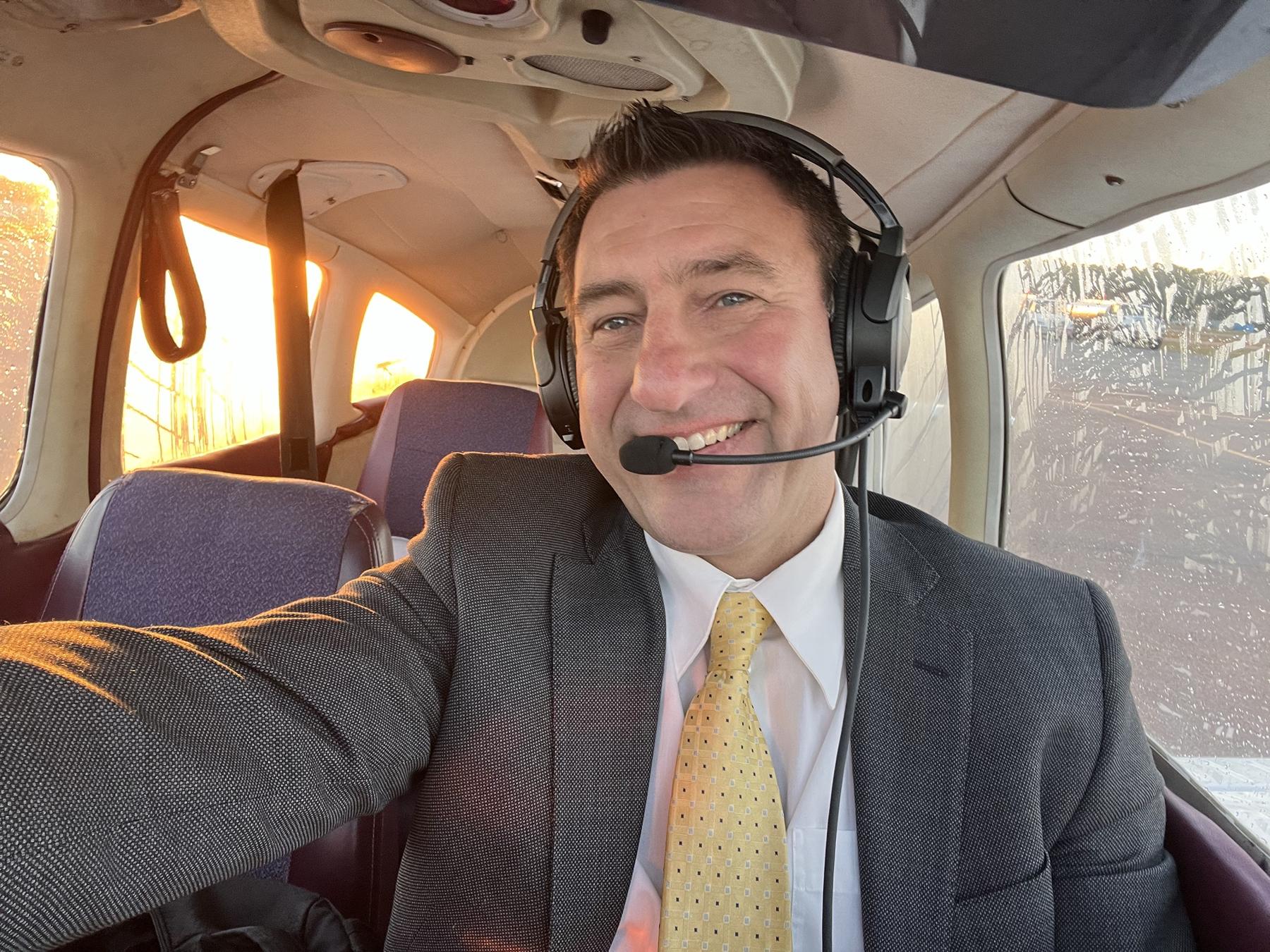 Julian Doby in a suit and headset in his plane at sunrise